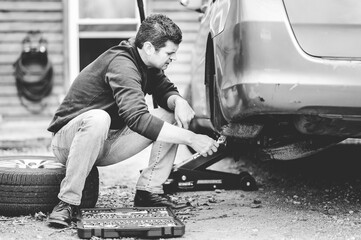 Sticker - Grayscale shot of a man repairing a wheel