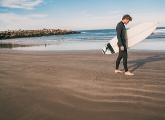 Surfer standing in the ocean with his surfboard.