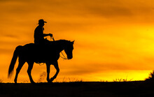 Horse And Rider Cowboy Silhouette At Sunset Western Rider In Western Tack Against Red Orange Sky
