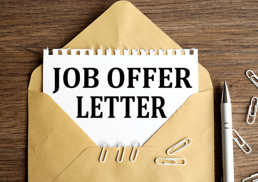 JOB OFFER LETTER. text on white paper on craft envelope on wood background