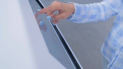 Woman hand using interactive touchscreen display of white electronic multimedia terminal at modern museum or exhibition - close up. Education, innovation, futuristic and technology concept