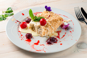 Poster - Light dessert classic Napoleon or millefeuille cake decorated with mint and strawberries. On a white plate, on a white wooden table