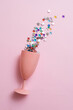 It's spilled drink of colorful stars from a pink glass on a pastel pink background. Minimal party concept. Flat lay.
