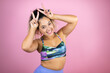 © Irene - Young beautiful woman wearing sportswear over isolated pink background Posing funny and crazy with fingers on head as bunny ears, smiling cheerful
