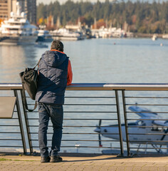back view of the man with luggage bag standing by the harbour. autumn season. travel photo, street v