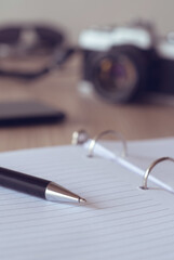 Poster - Vertical selective focus shot of a pen on the blank notebook paper - education concept