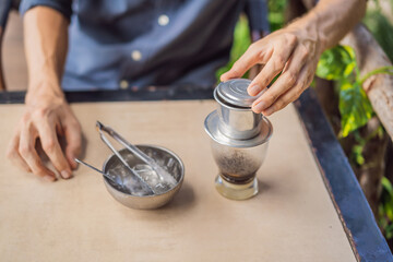 Caucasian man and traditional drip brewed Vietnamese coffee from a phin filter