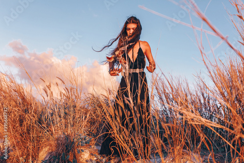 Plakat beautiful young fashionable woman on the beach at sunset