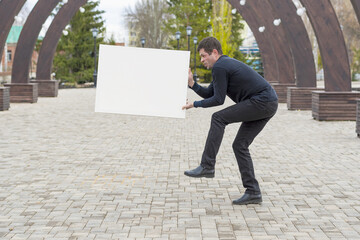 Wall Mural - The man holds before himself a white canvas for drawing and pushes it aside