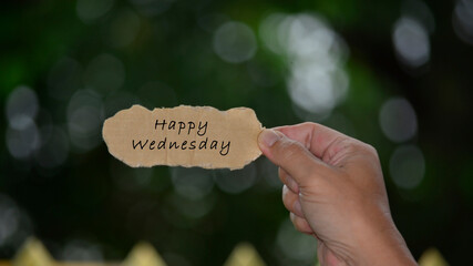 Wall Mural - Happy Wednesday Text On Hands Holding Torn Paper With Blurred Dark Background