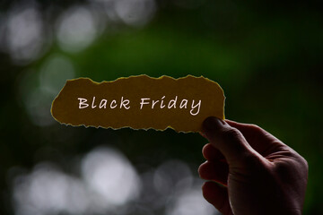 Wall Mural - Black Friday Text On Hands Holding Torn Paper With Blurred Dark Background