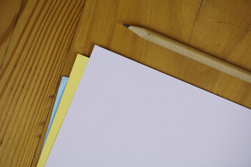 Canvas Print - Pencil and colorful sheets of paper on a wooden table