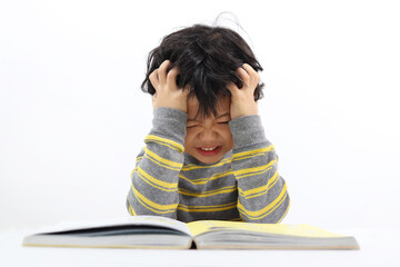 Wall Mural - Little Asian boy frustrated over homework with his both hand on his head. Boy studying at table isolated on white background.