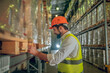 © zinkevych - Warehouse worker in yellow vest fixing boxes on the shelves