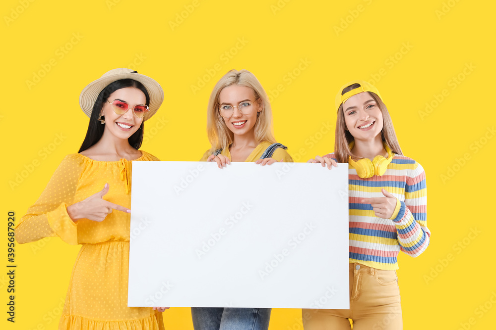 Beautiful young women with blank poster on color background