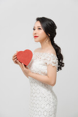 Beautiful girl holding love red gift box while standing isolated over white background.