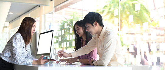 Group of web designers are working together to develop a mobile responsive website in meeting room.