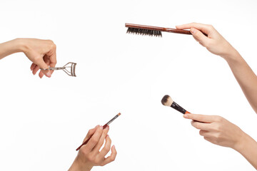 Hands with different makeup products on the white background.