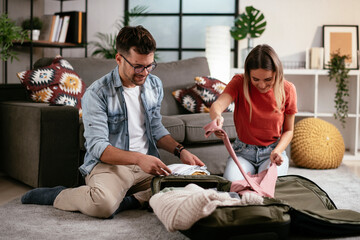  Loving couple packing clothes into travel bag. Boyfriend and girlfriend preparing for the trip.