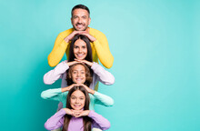 Photo Portrait Of Full Family With Small Children Stacking Heads On Top Of Each Other Next To Copyspace Isolated On Vivid Turquoise Colored Background