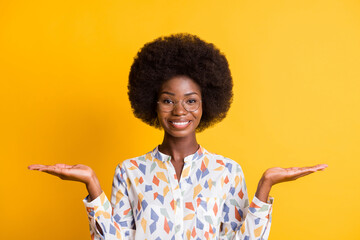 Sticker - Photo of pretty dark skin woman wear casual outfit spectacles holding two arms palms empty space isolated yellow color background