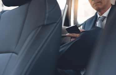 Wall Mural - Asian businessman browsing internet on mobile phone inside a car