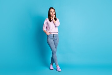 Full size photo pretty charming lady good mood touch neck cheek dreamer street look walk nice weather day wear casual purple sweatshirt pullover footwear jeans isolated blue color background