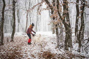 woman with dog walking in frost covered forest in winte