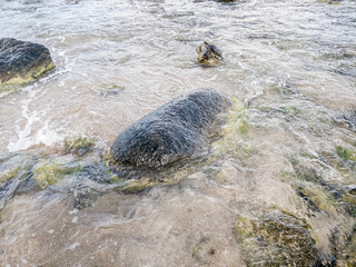 Beach on the sea with waves and stones in water