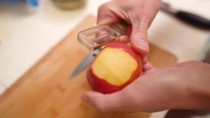 Wall Mural - Woman peeling fresh red apple over wooden plate