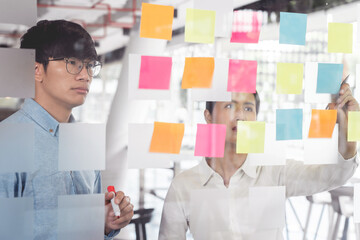 Wall Mural - Business manager showing idea for her team and stick many memo paper on glass window to success working in business meeting  creative office, planning and management concept.