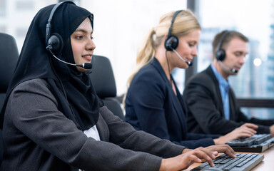 Female customer services agent with headset working in a call center.