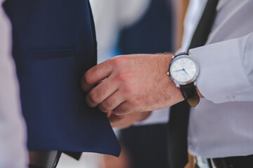 Wall Mural - Man with a shirt and a watch touching a blue suit