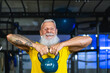 © Alessandro Biascioli - Senior fitness man doing kettle bell exercises inside gym - Fit mature male training in wellness club center - Body building and sport healthy lifestyle concept
