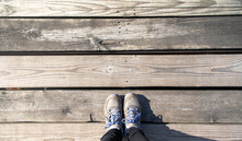 Closeup A Person Feet In Sneakers And Jeans Standing On The Old Wooden Floor Plank