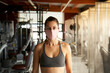 © CarlosBarquero - Young woman with sportswear with face mask looking at camera in gym.