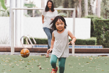  Asian 3 year old kid and mom play football in park. Background for  funny life and family play time.