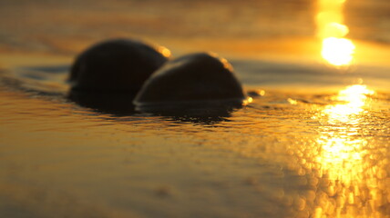 black pebbles sunset light reflection on a Mediterranean beach 