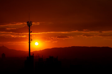 city skyline and cell tower under sunset