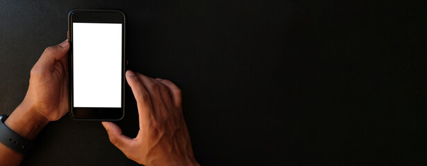 Wall Mural - close up shot of man hands holding mobile phone with blank screen on black background with copy spac