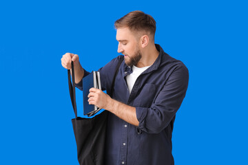 Wall Mural - Young man with books on color background