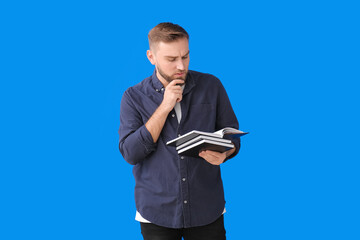 Sticker - Thoughtful young man with books on color background