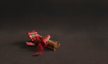 Cinnamon Sticks Tied With Red Ribbon On Brown Velvet Background