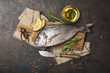 Fresh fish dorada or gilt-head bream on cutting board with spices, olive oil and lemon