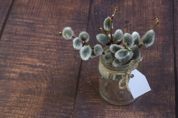 spring or Easter theme: willow twigs in a transparent jar with a tag on a dark wooden background