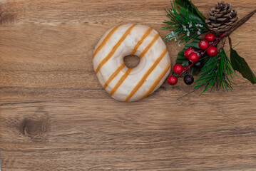 Donut in glaze and festive pine branch on wooden natural background