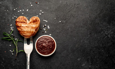 Wall Mural - Heart shaped grilled pork steak on a fork for valentine's day on stone background with place for text