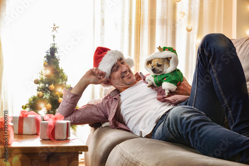 Fotomural Man resting on sofa with dog dressed in christmas costume
