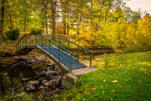 Autumn Fall Color Landscape. Small Footbridge Over A Creek Surrounded By Vibrant Fall Foliage At A Small County Park In Jackson County, Michigan.