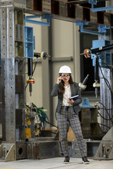 Wall Mural - Portrait of a female factory manager in a business suit holding notebook, controlling the work process in the manufacturer.	